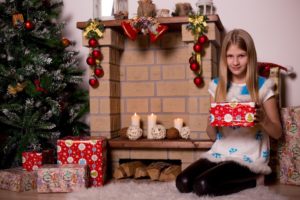 petite fille découvre ses cadeaux devant le sapin de Noël